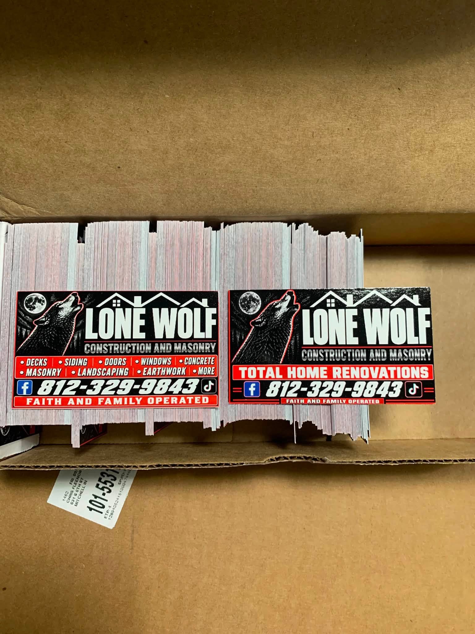 A box of freshly printed Lone Wolf Construction and Masonry pieces in two layouts